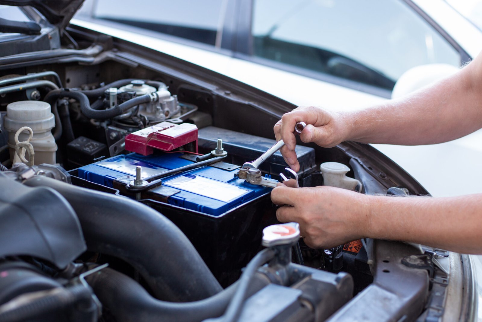 A,Man,Tightens,With,A,Wrench,Bolts,For,Fastening,A Battery Replacement on a car